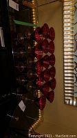16 red topped Mikasa martini glasses arranged on a surface with lighting reflecting on them.