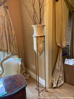 Full view of off-white ceramic vase on gold-tone metal tripod stand