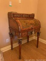 Three-quarter front view of roll-top desk showing overall form, inlaid wood veneer and gallery rail.