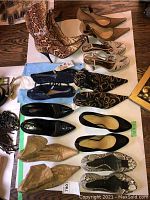 Six pairs of shoes arranged on white backdrop: snake-print boots; taupe pumps; silver sandals; black glitter TOMS; black/gold mules; black patent flats