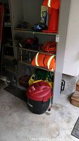 Photo shows a red Shop-Vac vacuum near shelves holding garden supplies, safety vests, and tools.