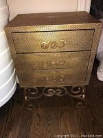 Front view of one side table showing three drawers with scrolled handles and decorative scrolled metal base.