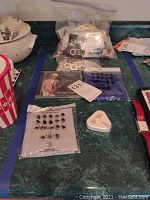 Photo of assorted items on table: bag of buttons, Lee England CD, earbuds, face protection cloth.