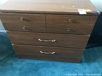 Front view of wooden 3-drawer chest showing metal knobs and handles with scratches.