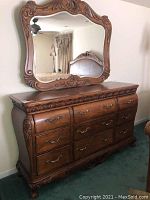 Front view of 9-drawer wooden dresser with matching carved frame beveled mirror