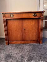 Full front view showing drawer, doors, fluted trim and finish condition
