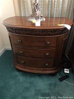 Pair of brown wooden nightstands with three drawers, decorative carved molding along top edge, and rounded fronts.
