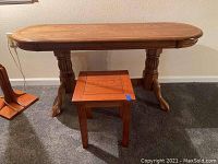 Oval oak hall table with carved claw feet and a small oak mission style square table in front on carpeted floor.