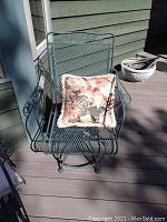 Front view of one metal outdoor swivel chair with a floral cushion placed on the seat.