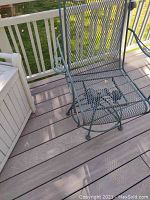 Metal outdoor chair with mesh seat and backrest on a deck.