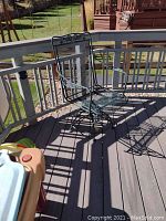 Single metal outdoor chair with mesh design and armrests on deck.