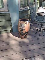 Side view of large ceramic planter pot showing geometric designs and crack near base