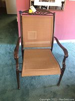 Full view of the metal and mesh patio chair with decorative metalwork on top rail, armrests, and mesh seating and backrest in brown.