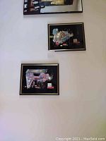 Pair of vertically-hung black lacquer panels featuring two Geishas in traditional dress on a white wall.