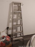 Full view of the 6 foot aluminum step ladder leaning against a wall, showing entire height and step configuration.