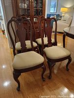 Four chairs arranged front view next to china cabinet showing overall set and styling