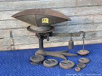 Full view of the vintage crows foot scale including base, hanging weight, and cast iron weights arrayed on a padded surface.