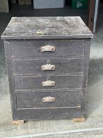 Front view of antique industrial wooden cabinet showing four drawers with metal handles and keyholes.