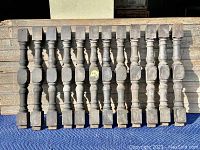 Full view of the 12 wooden balusters laid side by side showing entire lot.