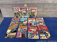 Full lot of 10 vintage comic books displayed together on blue moving blanket against wooden background.
