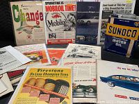 Collection showing Sunoco motor oil metal can alongside various vintage automotive advertisements and brochures.