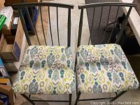 Two metal chairs with black spindled backs and blue-green patterned cushioned seats.