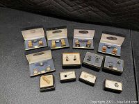 Full display of 12 pairs of cufflinks and tie pins in original Foster and Swank boxes, showing various styles and finishes.