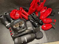 Fighting gear including black Rev Gear headgear and gloves alongside red Century shin and forearm guards.