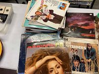 Stack of assorted vinyl records showing album covers including Genesis, The Outsiders, Nashville country artists, and others.