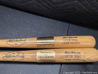 Two full-size Adirondack Big Stick Victor Moniz flame treated bats side by side showing upper halves and brass plaques