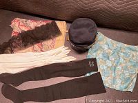 Full view showing the vintage floral patterned top in blue with gold patterns, white gloves, black lace scarf, black vintage hat, and black stockings laid out on a surface.