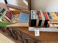 Photo of assorted books in a shallow box and some VHS movies on display