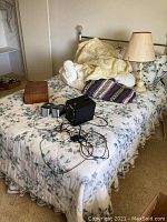Full view of the brass bed frame with floral bedding, lamp, speakers, and accessories arranged on the bed.