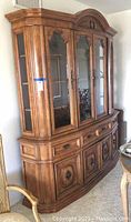 Full view of the wooden china cabinet with glass doors, drawers, and lower storage cabinets showing overall condition and style.