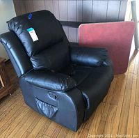 Black electric recliner and red card table shown from front-left angle. Recliner shows wear on right armrest.