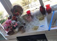 Wide view of glassware and floral arrangements displayed on counter in natural light.