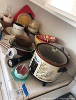 Photo showing various kitchenware items on a countertop including a Crockpot, glass and ceramic bowls, a flashlight, and plastic cutting boards.