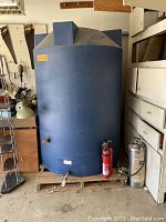 Full view of blue cylindrical tank on pallet with spigot and drain port visible