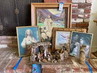 Overview of nativity scene, framed religious artworks, wooden plaque, and decorative tin displayed together on a brick hearth.