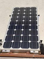 Front view of the solar panel showing the photovoltaic cells actively mounted in a metal frame with wheels on the bottom side.