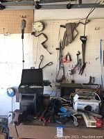 Overview of workshop table with tools including pliers, saws, metal vise, and various power cords and boxes.