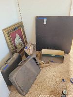 Photo showing vintage briefcase, framed artwork, iron heater, and miscellaneous small boxes and tubes