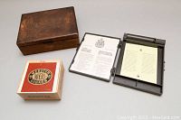 Photo of the closed wooden cigar box, Webster box, and vintage stamp holder with informational leaflets.