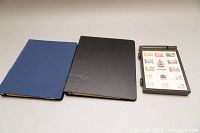 Closed view of two binders and one smaller album containing stamps