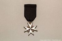 Front view of enamelled silver Maltese cross medal pinned to black ribbon