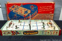 Overview of the tabletop hockey game with players arranged on the rink and the original box in the background.