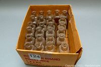 Top view of 24 vintage apothecary glass bottles arranged in box