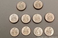 Top and side view of multiple Canadian 50 cent coins showing the Canadian Coat of Arms reverse design.