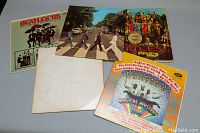 Photo showing all five Beatles album covers: Beatles '65, Abbey Road, Sgt Pepper's, White Album sleeve, Magical Mystery Tour.