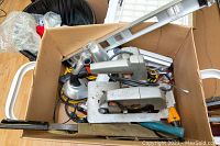 Box full of various tools showing circular saw, level, rope, and other hand tools